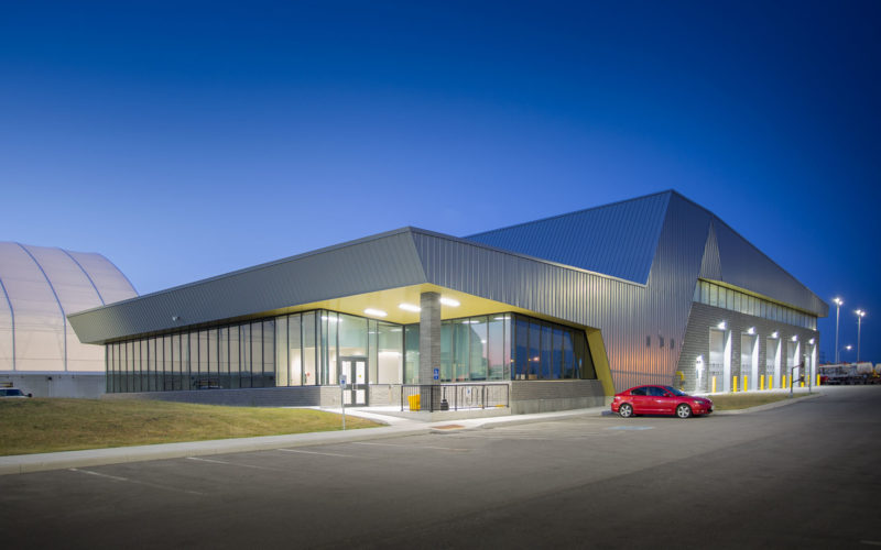 Exterior night photo of the facility with the parking lot in the front