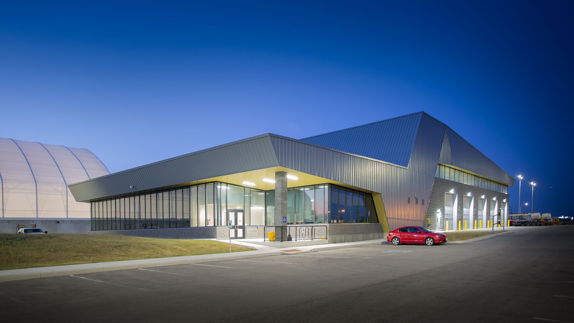 Exterior night photo of the facility with the parking lot in the front