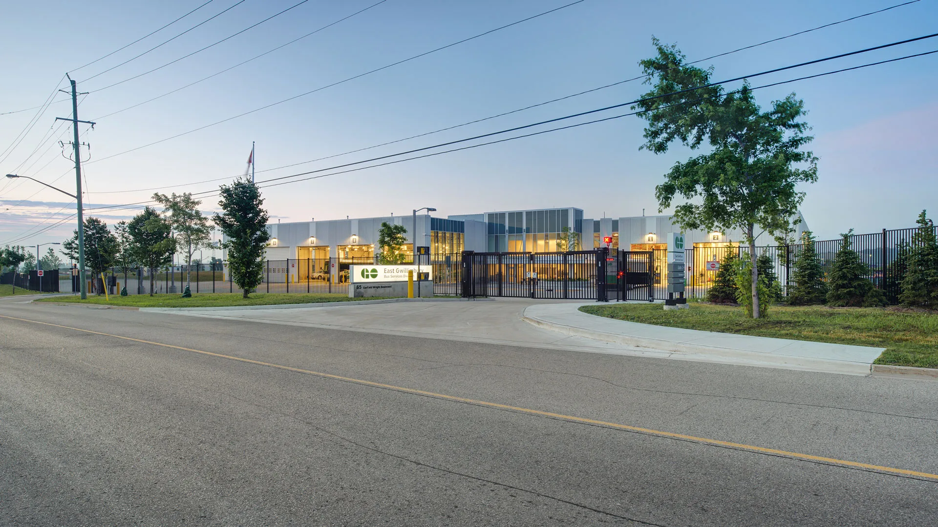 Exterior photo of the facility, showing the entire building, the gate and the road