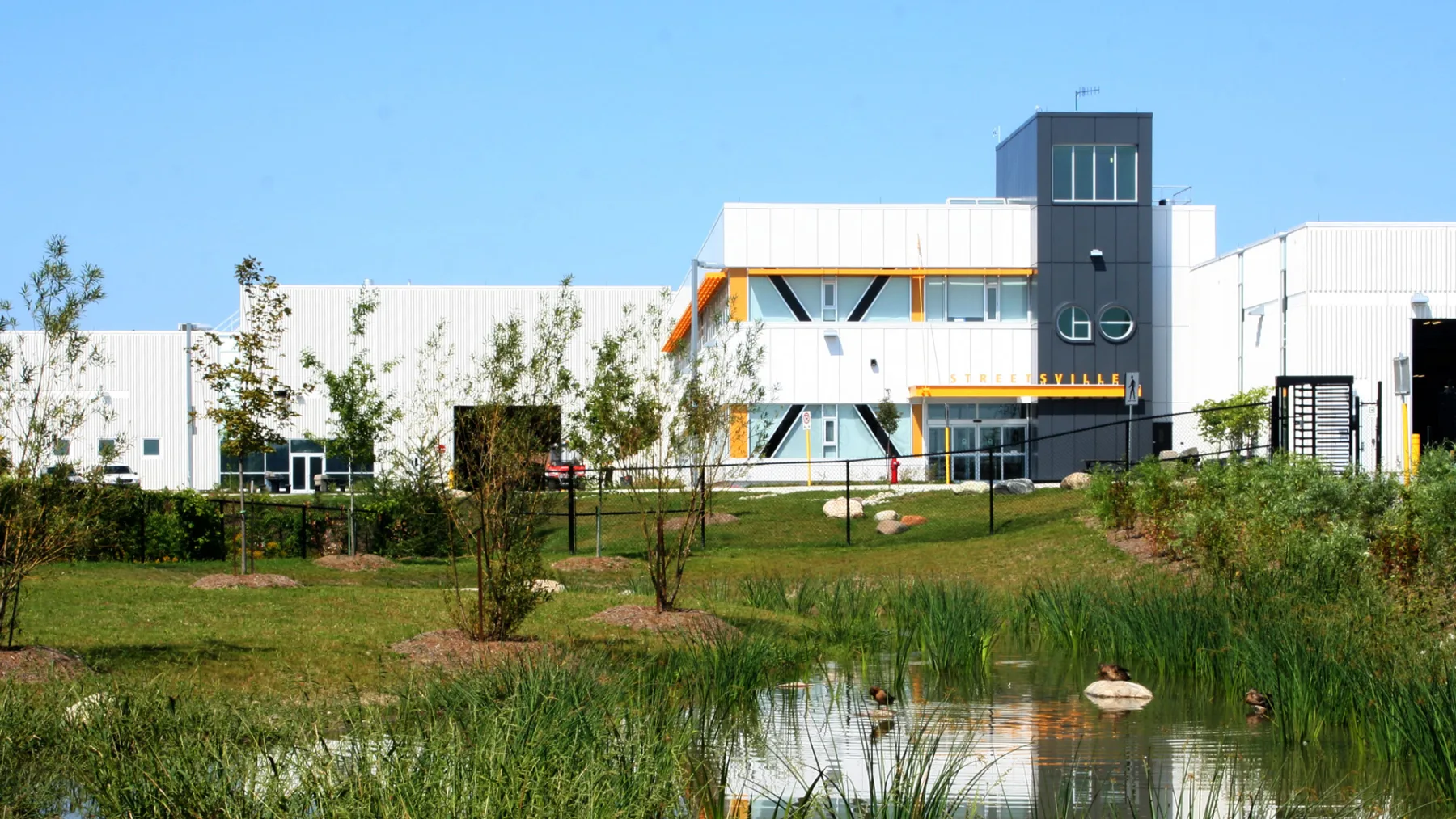 Exterior photo of the facility showing the building, landscape and a pond