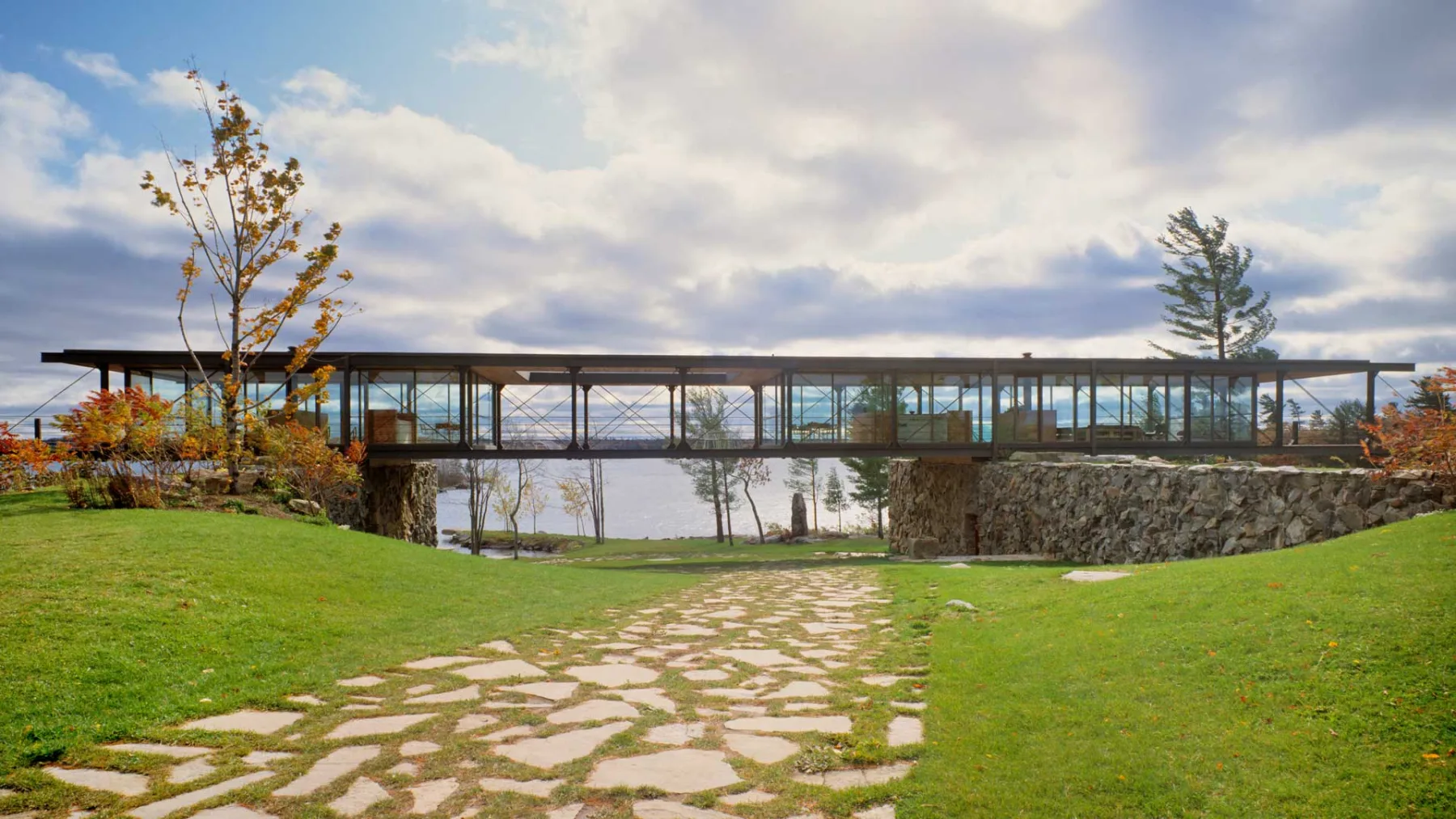 Exterior photo showing the residence in entirety surrounded by grassland and the lake in the back