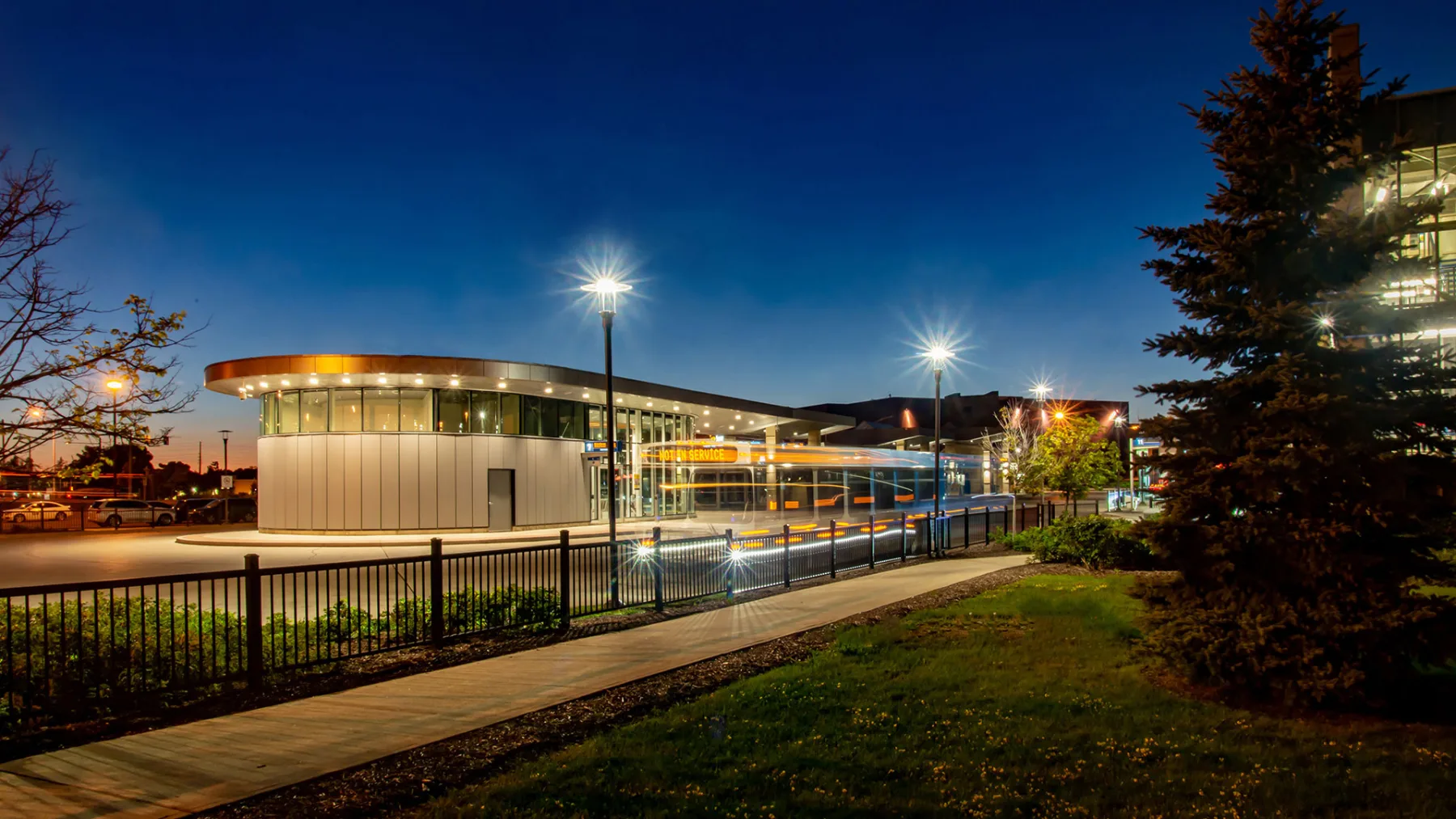 Exterior photo of the bus terminal at night, with a bus passing by