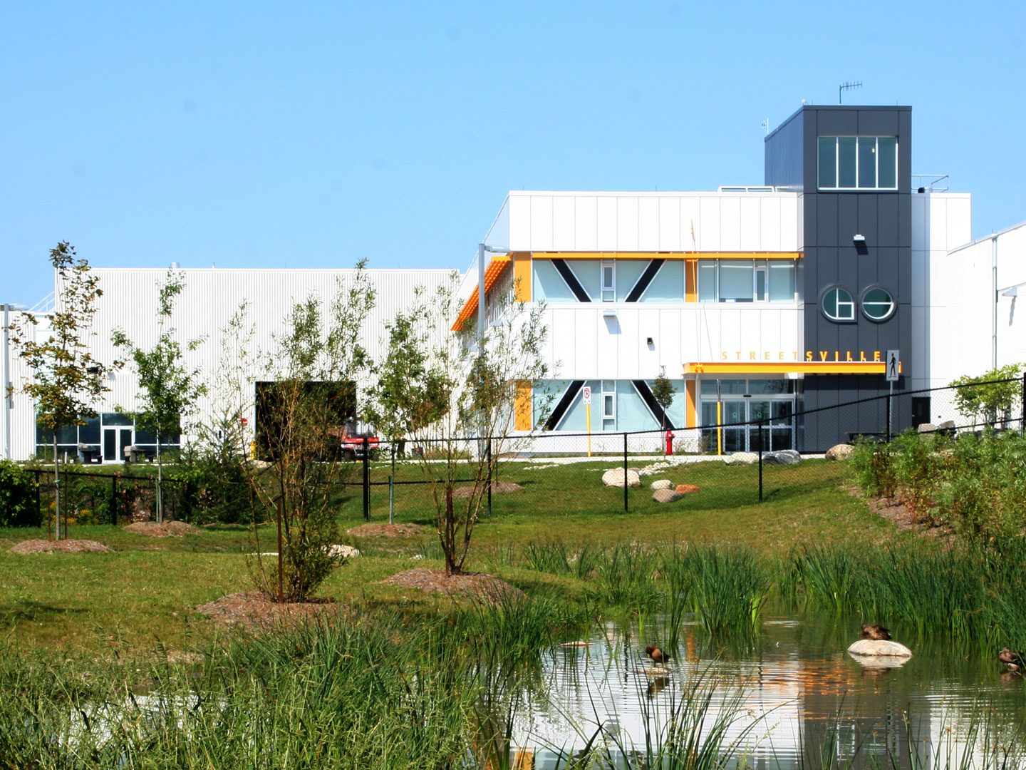 Exterior photo of the facility showing the building, landscape and a pond
